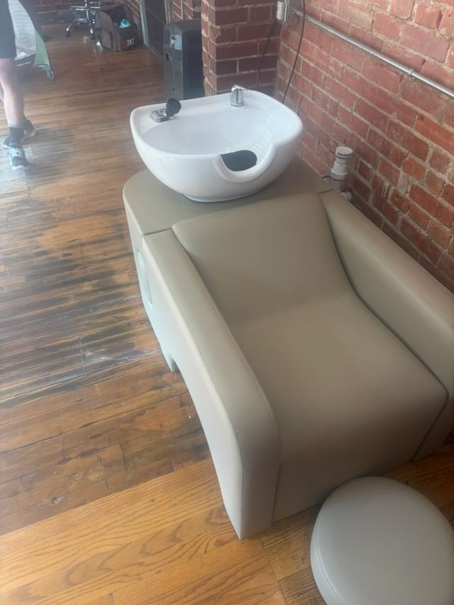 Salon shampoo bowl and chair plumbed in against a brick wall