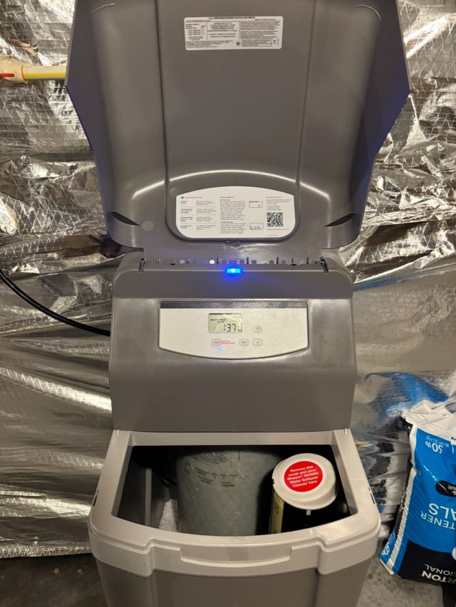 Water softener with the lid open and the control panel powered on